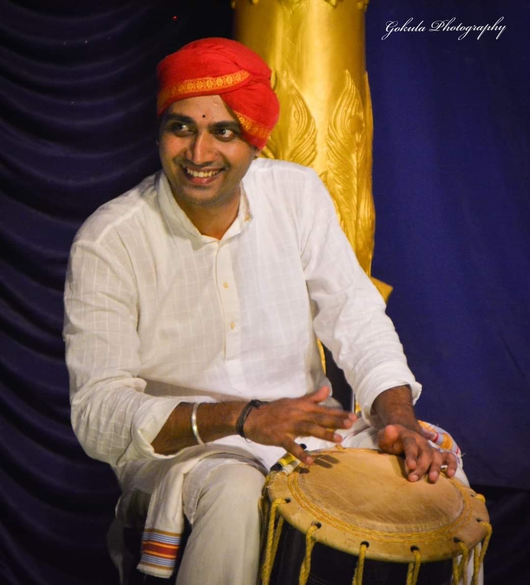 A drummer, dressed in white shirt plays the vertical drum