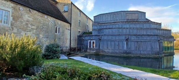 An exterior shot of the mainReal World Studio, build as an extension onto an old water mill made of Bath stone. The sun is shining, and there is running water in the foreground