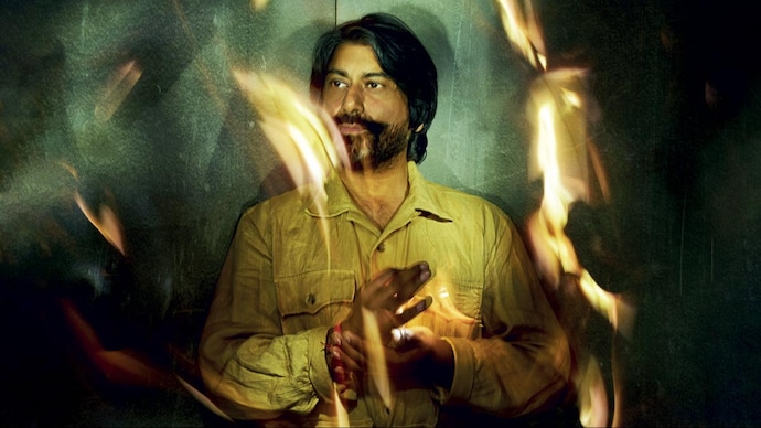 A stylised photograph of Talvin Singh, holding his tabla, with green and lighting blurs across the photo.
