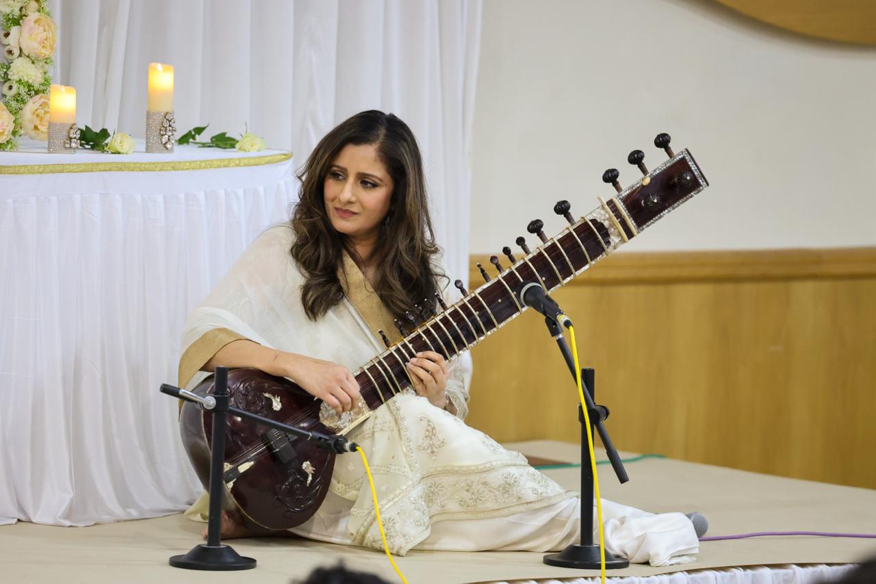 Roopa Panesar, dressed in a white and gold saree, seaed on stage with her sitar.