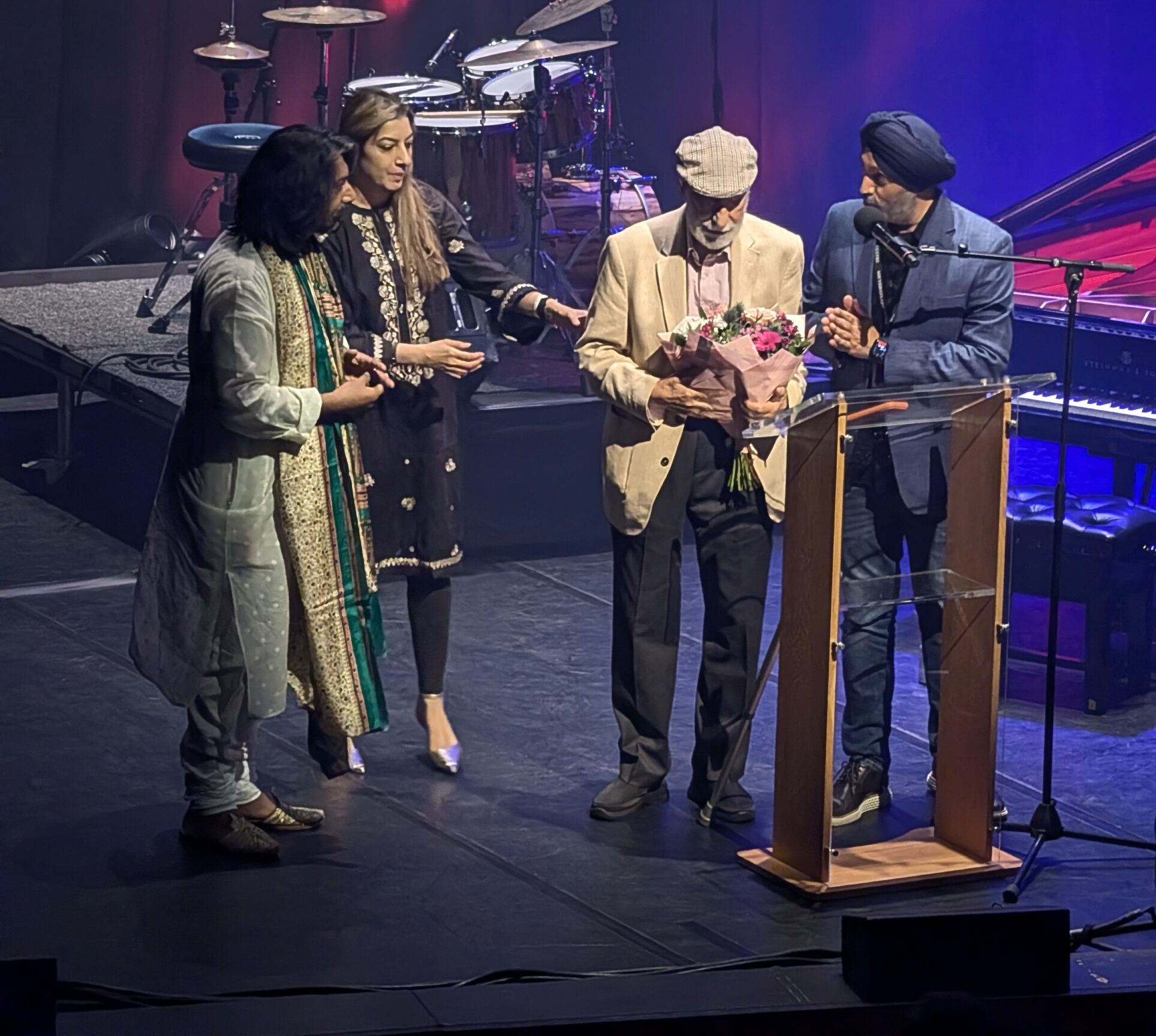 Jaswinder Singh, Asian Arts Agency director on stage with members of Zakir Hussain's family