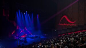 The Queen Elizabeth Hall at Southbank Centre, set for a performance, bathed in red and purple light. A full-house are seated, awaiting the start