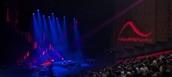 The Queen Elizabeth Hall at Southbank Centre, set for a performance, bathed in red and purple light. A full-house are seated, awaiting the start