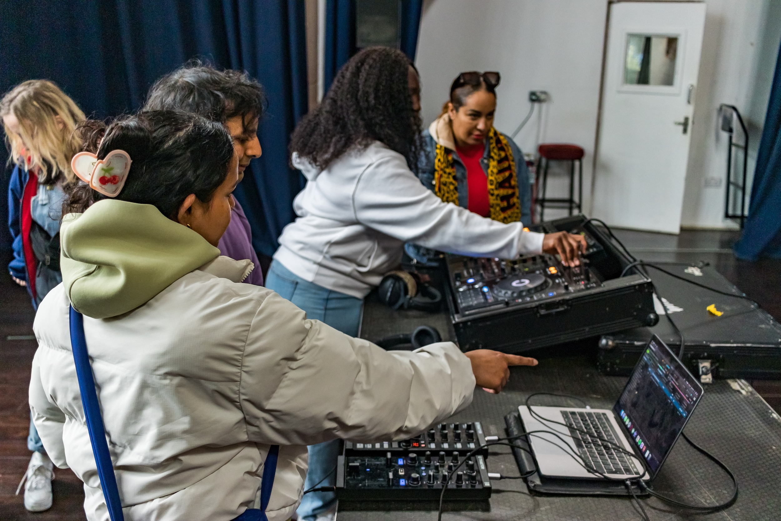 A DJ workshop taking placed, two children in the foreground, shot from behind, playing with the CD decks.